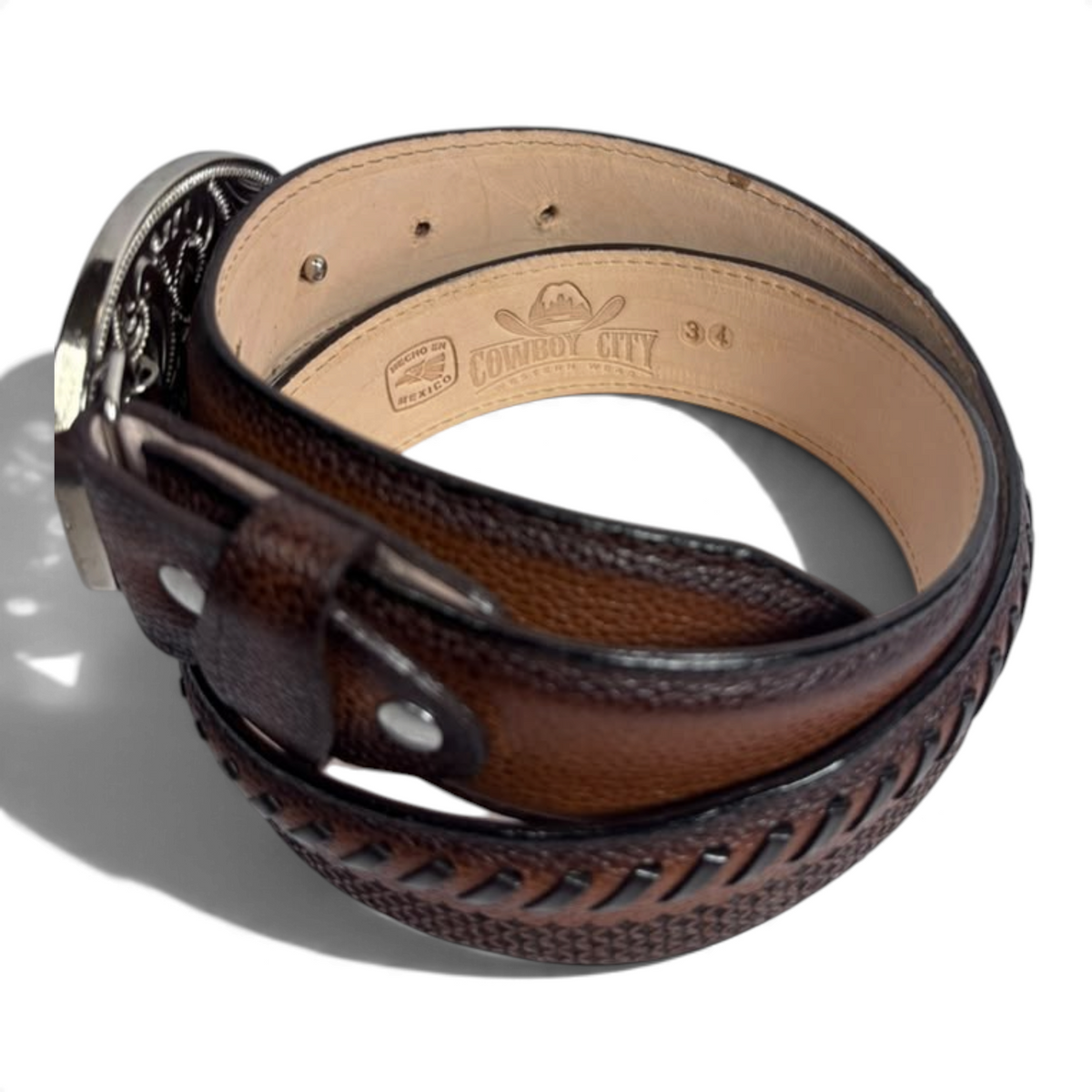 Cowboy City Western Wear brandy leather belt with laser-tooled design and signature C buckle, coiled on white surface.
